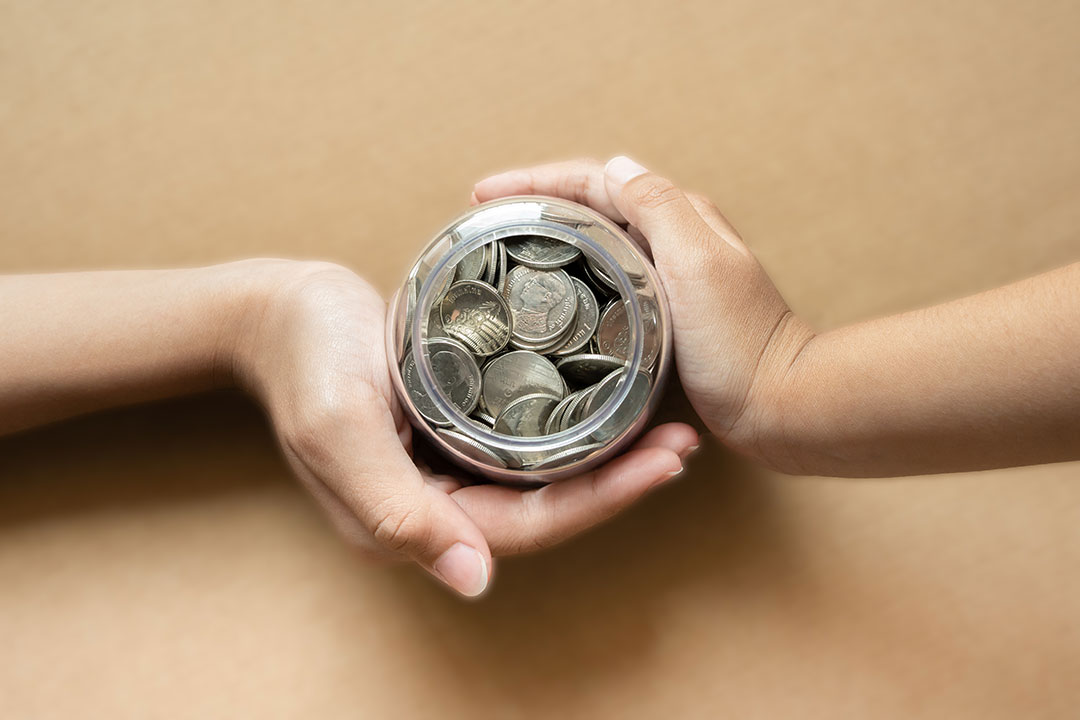 Two hands holding a jar of coins