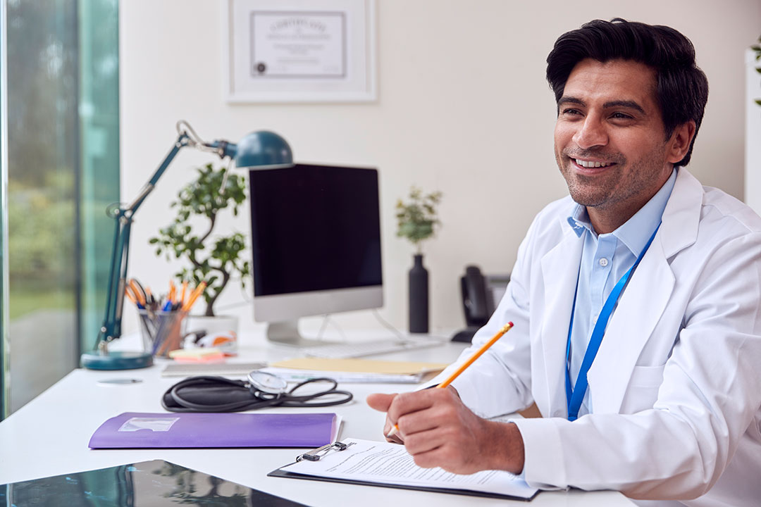 A smiling doctor giving a consultation over a desk