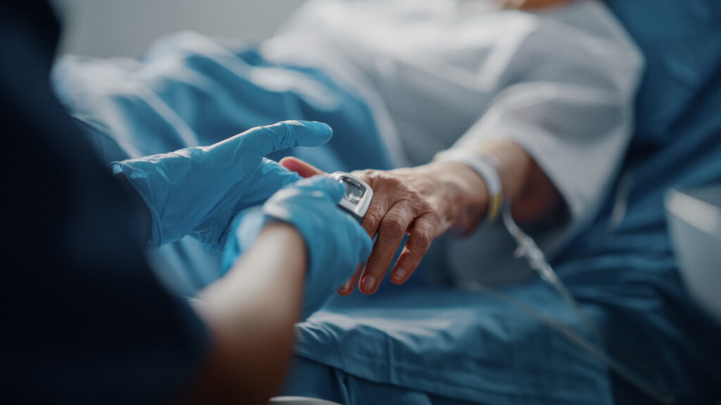 Close up of a doctor holding the hand of a patient in a hospital bed