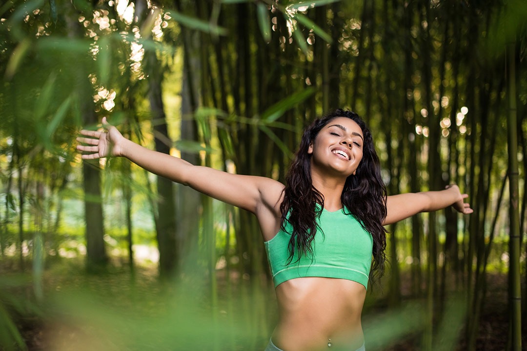 Woman stretching her arms in bamboo garden